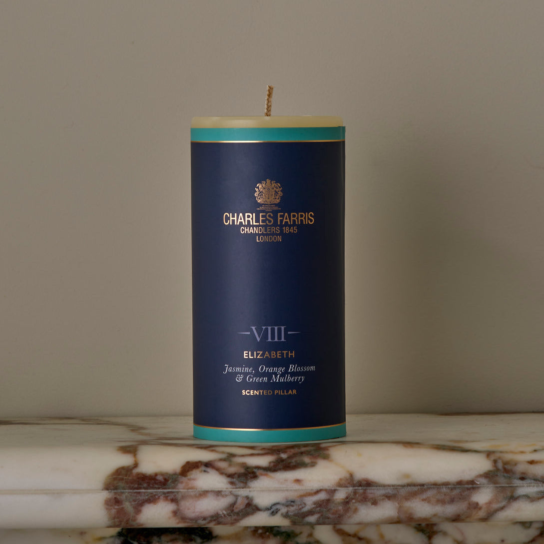 Candle with a blue label featuring Charles Farms branding on a marble surface.