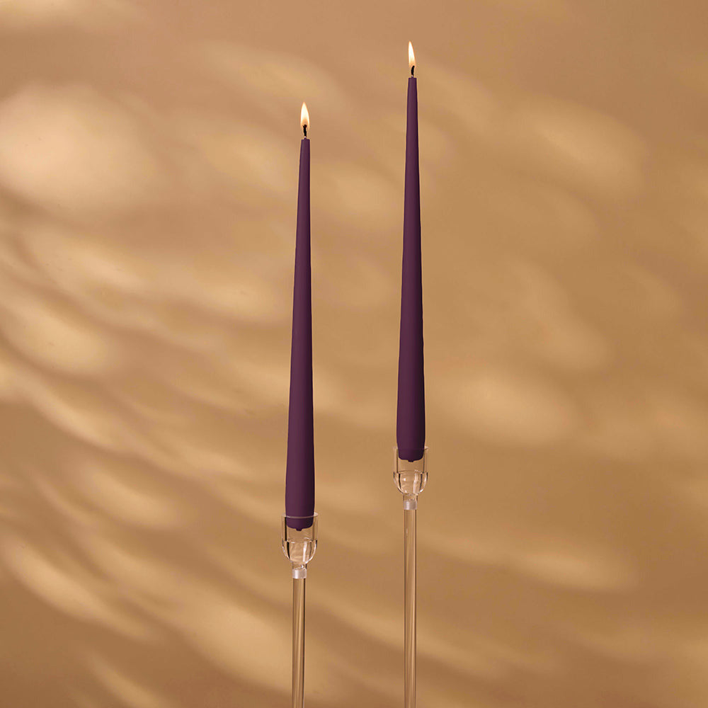 Two purple candles with clear holders on a beige background