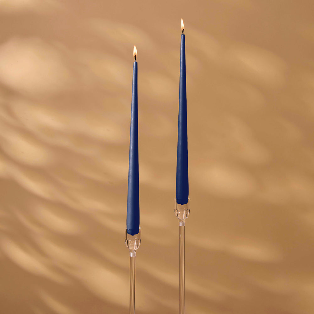 Two blue candles with clear holders on a beige background