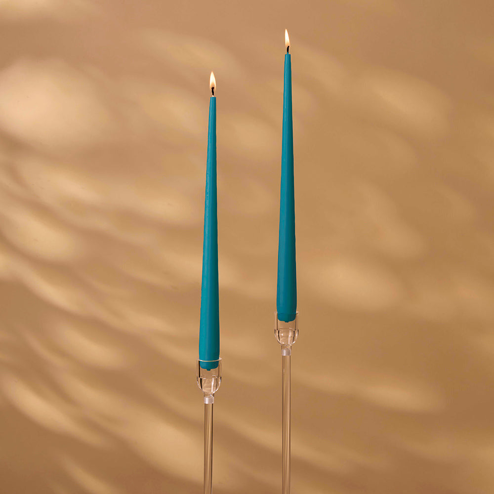Two blue candles with clear holders on a beige background