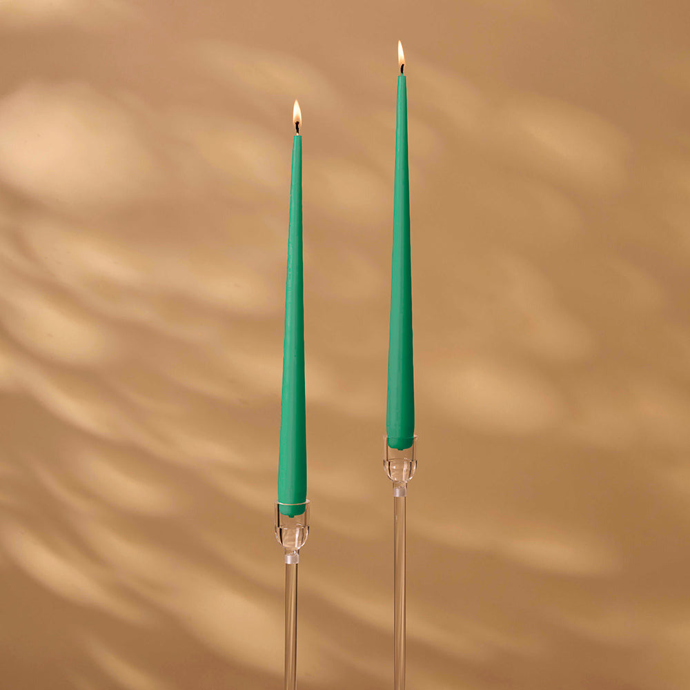 Two green candles with clear holders on a beige background