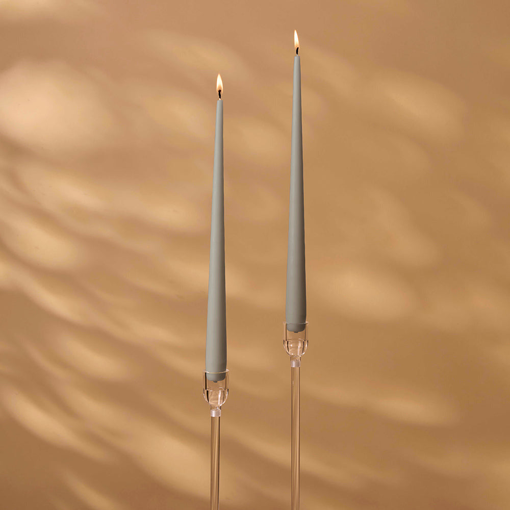 Two gray candles with clear holders on a brown background