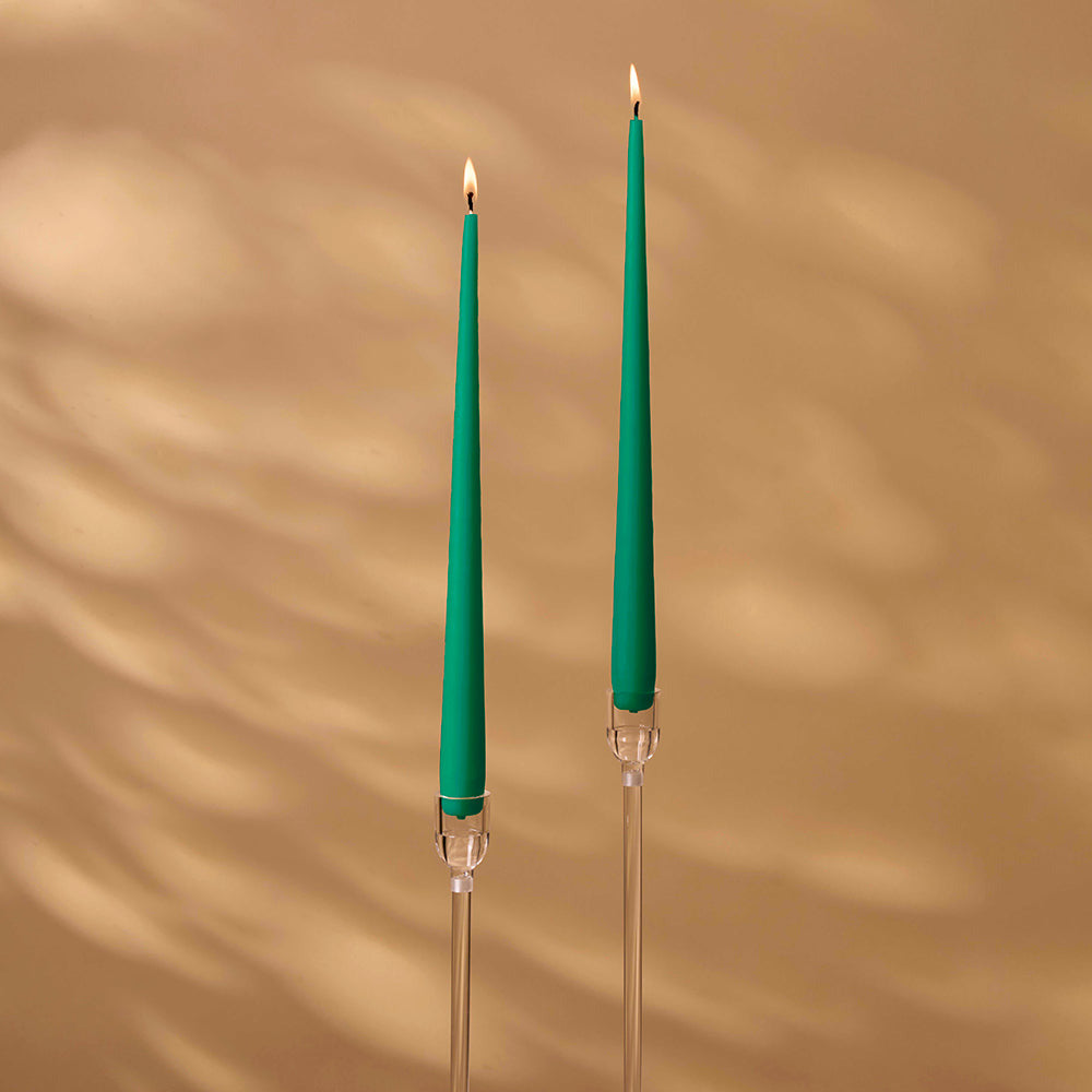 Two green candles with clear holders on a beige background