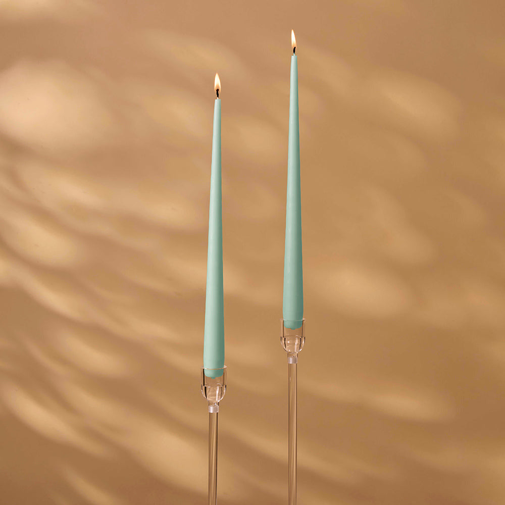Two teal candles with clear holders on a brown background