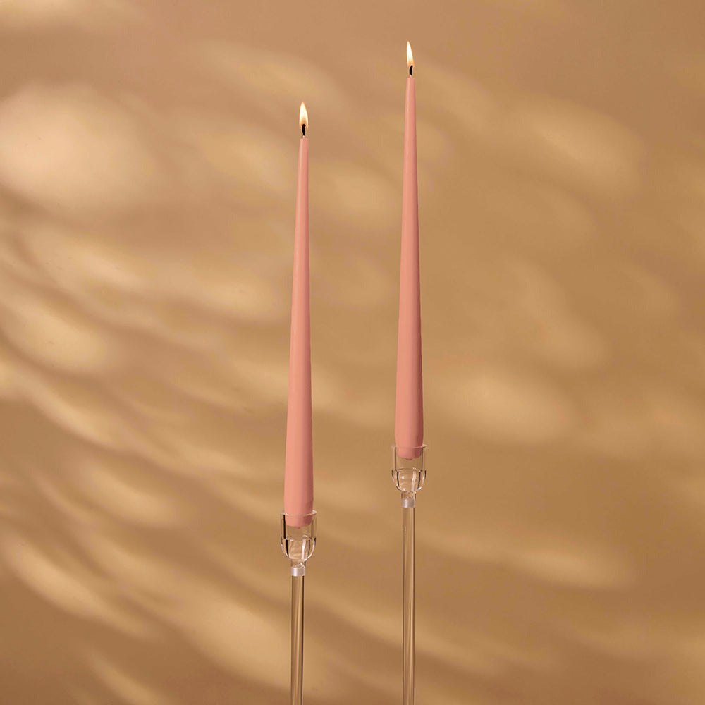 Two pink candles with clear holders on a beige background