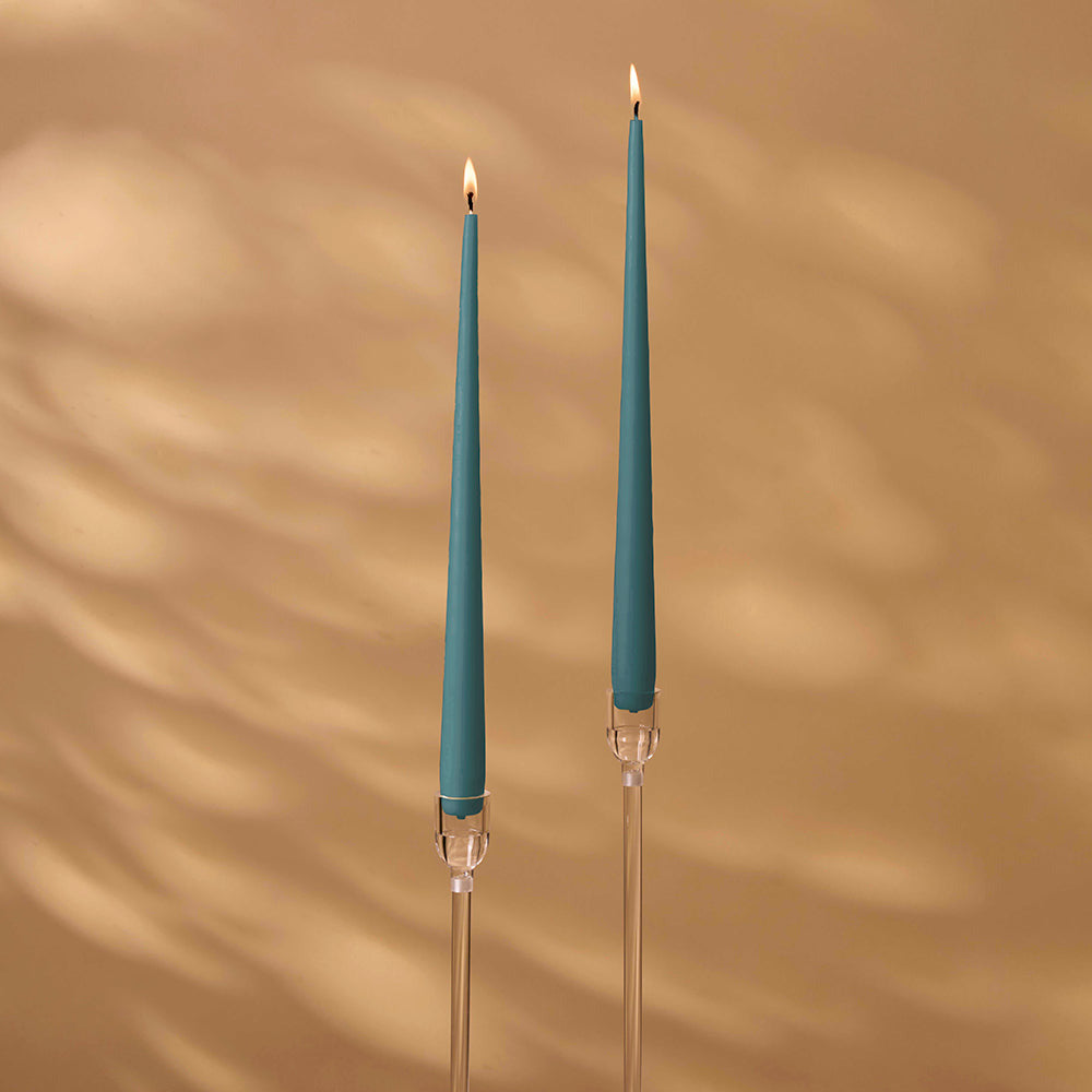 Two teal candles in clear candle holders with a beige background