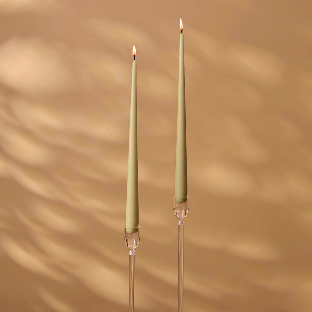 Two green candles with clear holders on a beige background