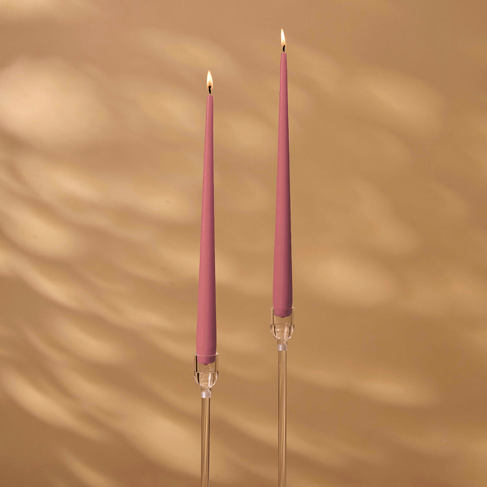 Two pink candles with clear holders on a beige background