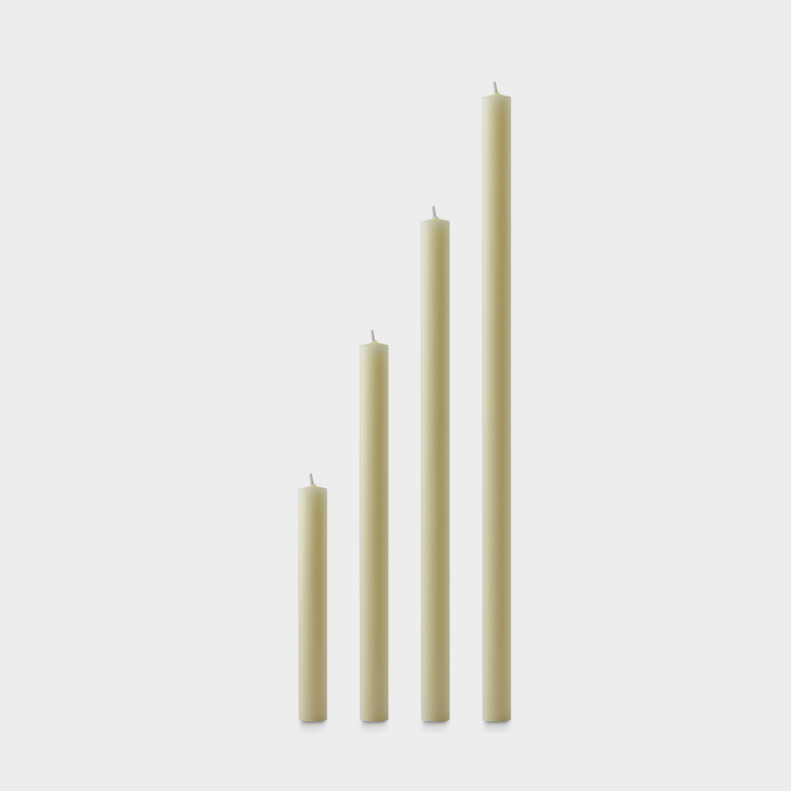 Set of four ivory beeswax candles of varying lengths on a white background