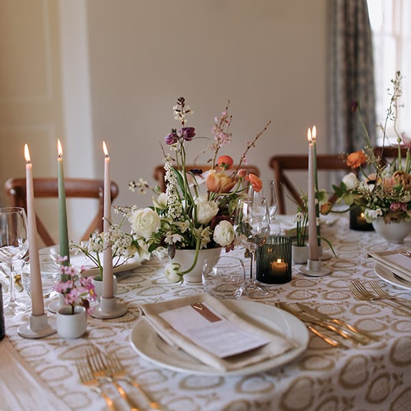 Elegant table setting with floral centerpieces, candles, and place settings.