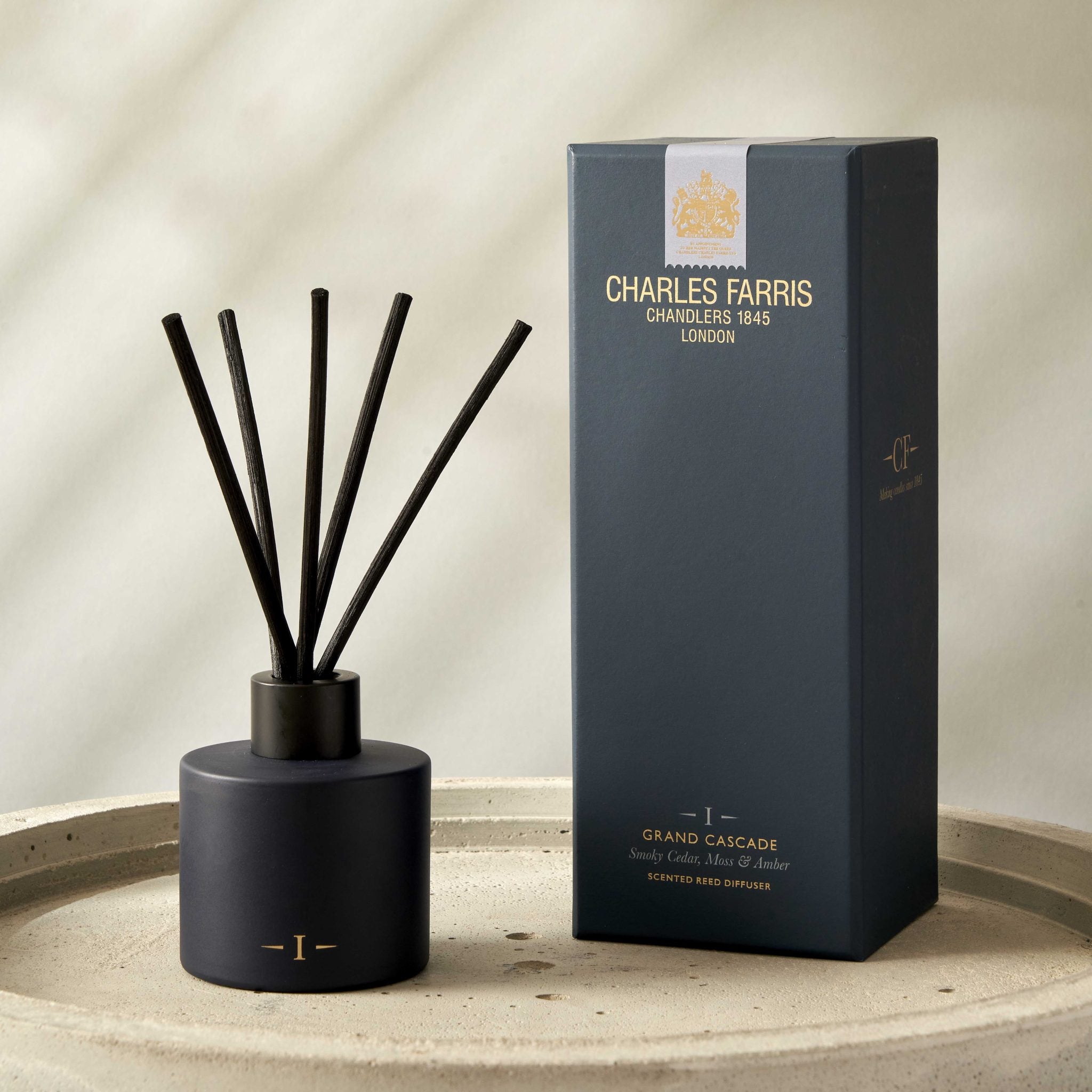 Black diffuser with sticks and its packaging on a beige surface