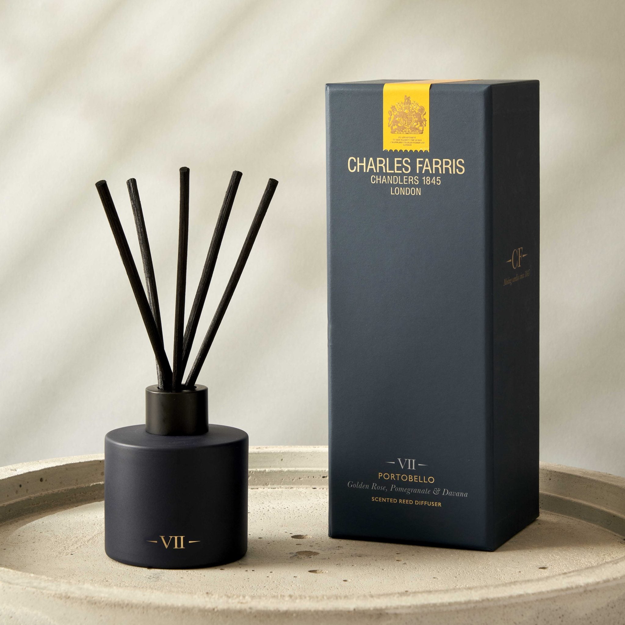 Dark blue Portobello reed diffuser with sticks and its packaging on a concrete surface