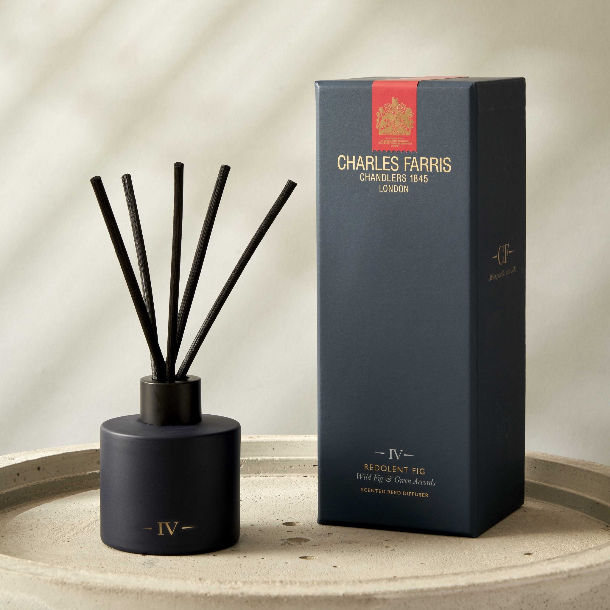 Reed diffuser with sticks and its packaging on a beige surface