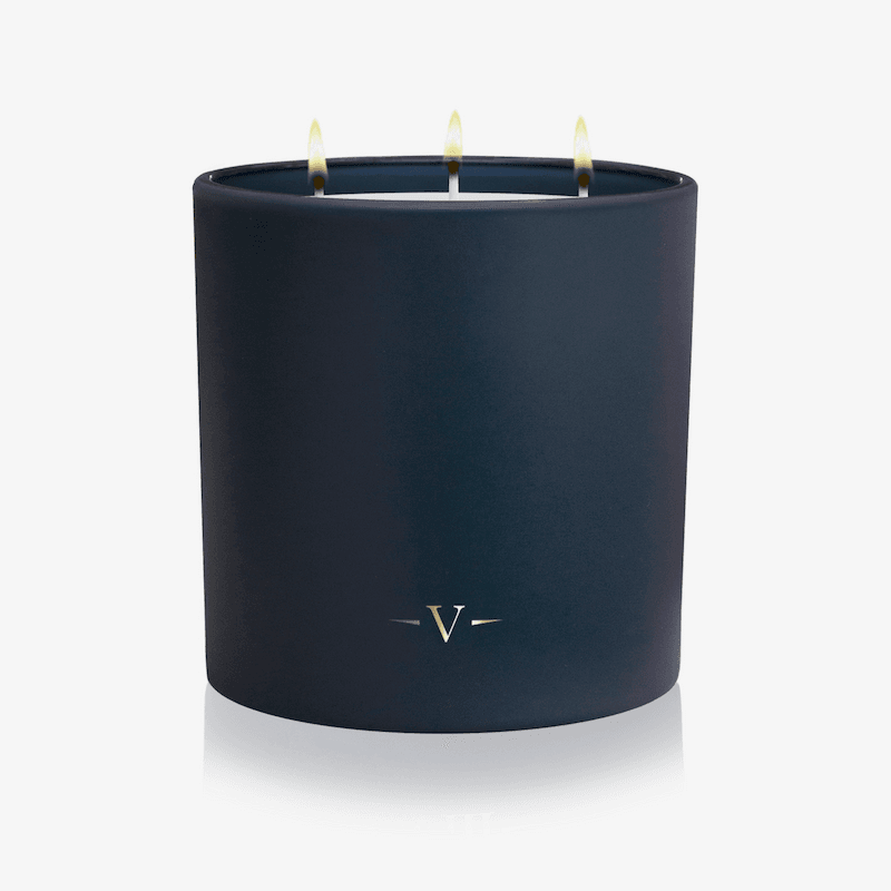 Navy blue candle with a visible brand logo on a white background