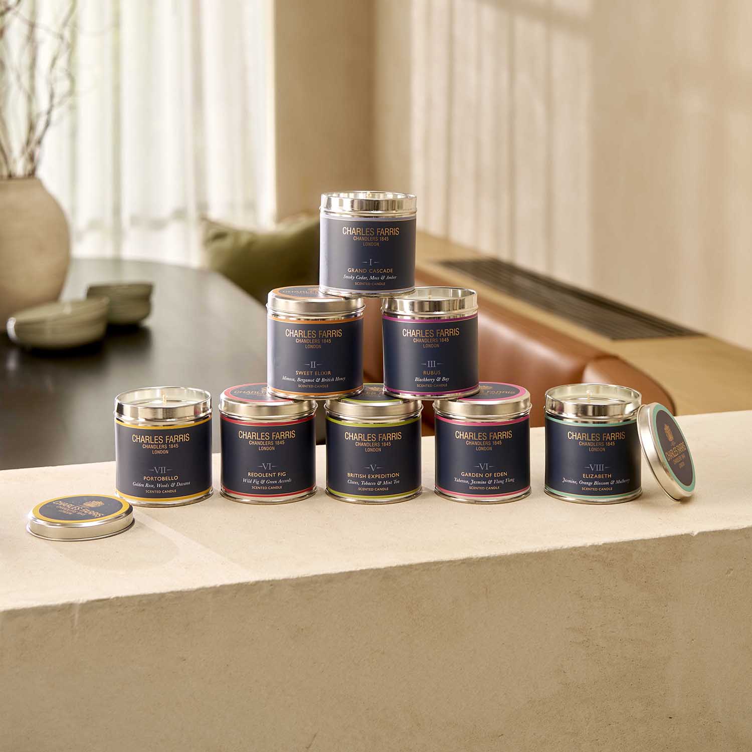 Collection of candles with Charles Farris branding on a surface.