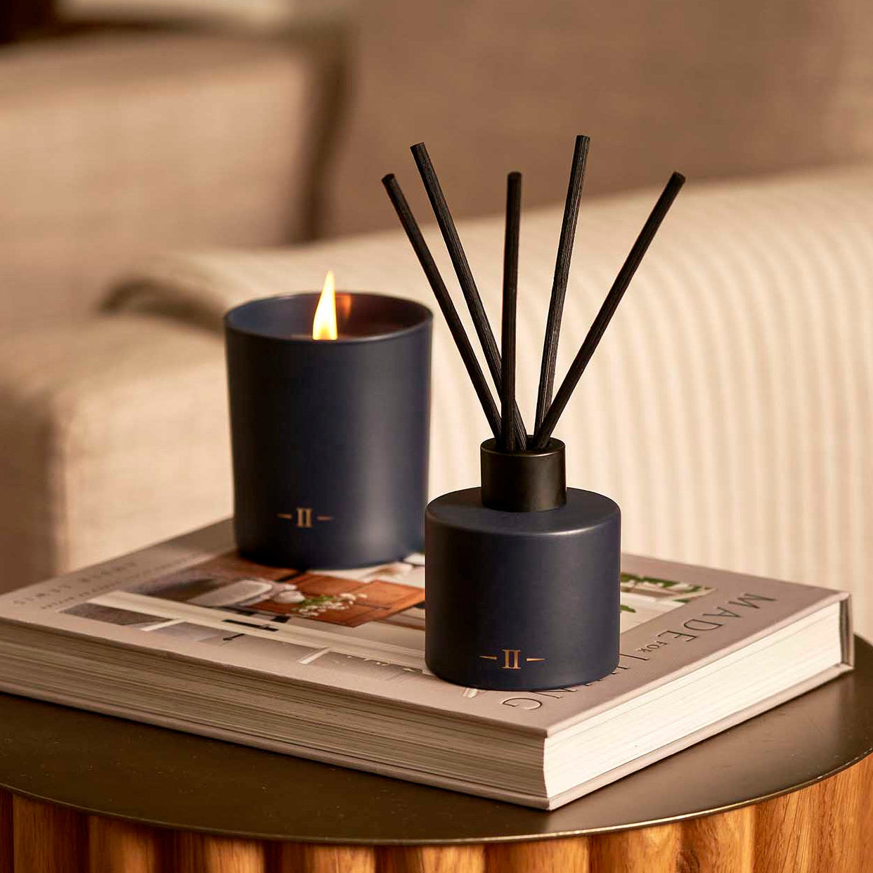 Navy blue diffuser and candle on a book with a blurred background