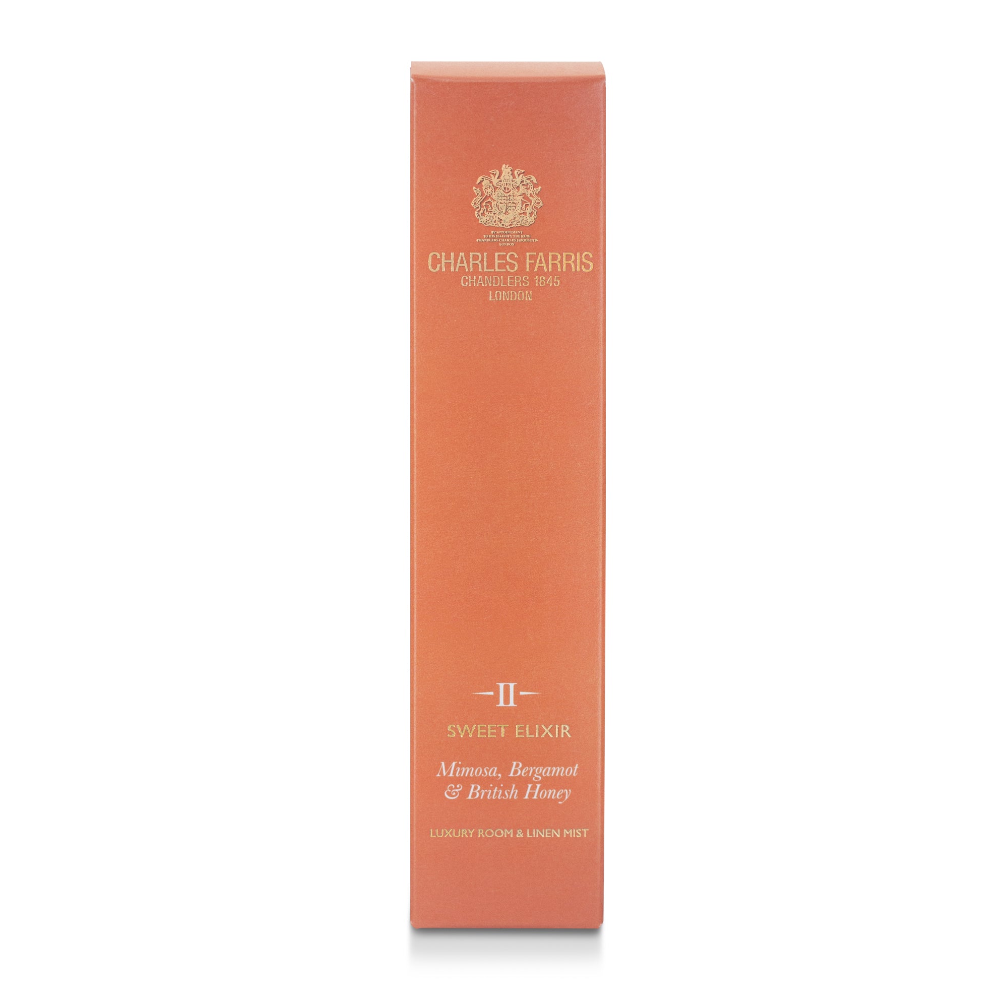 A tall, narrow peach-colored box for Charles Farris Sweet Elixir room spray fragrance mist with mimosa, bergamot, honey featuring gold lettering and a gold crest, set against a plain white background.