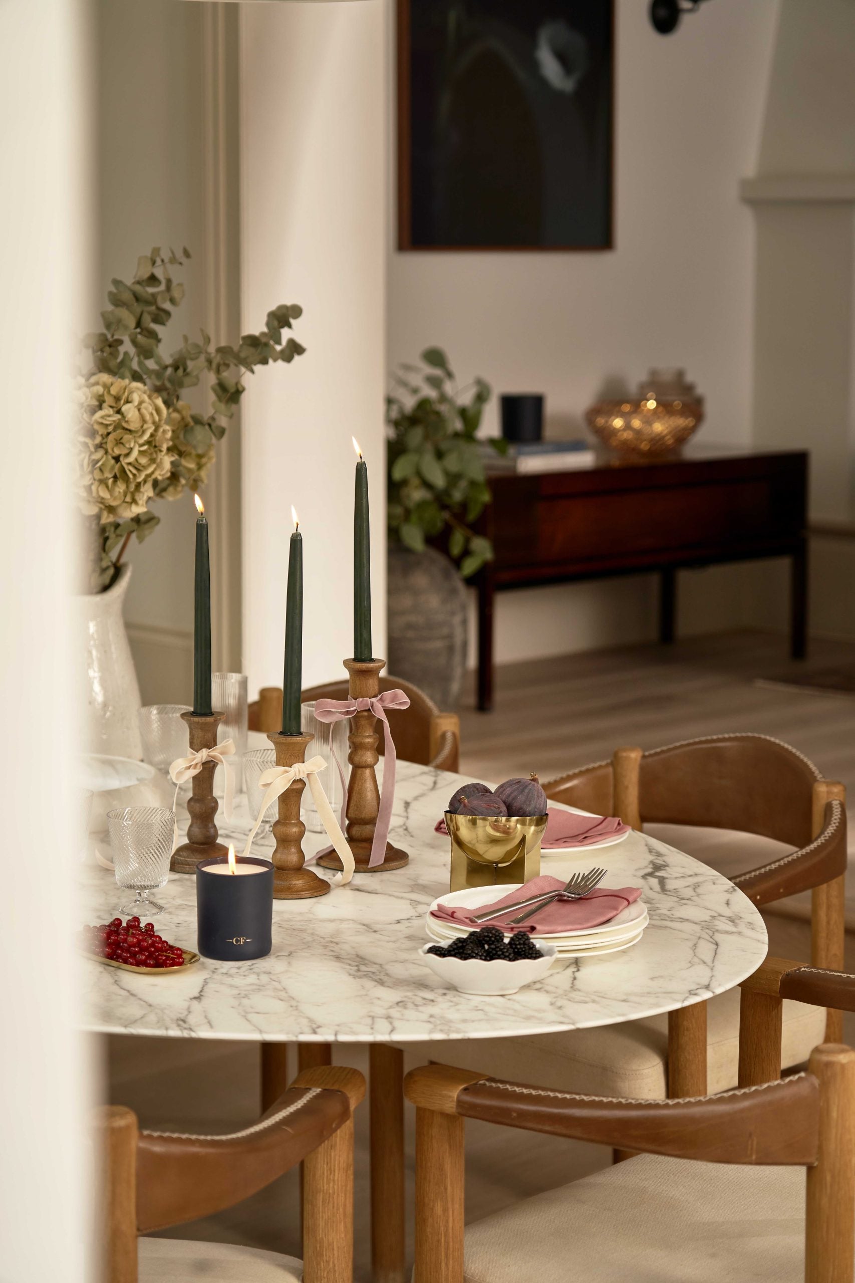 A table setting with green dinner candles and a 1wick Charles Farris candle 