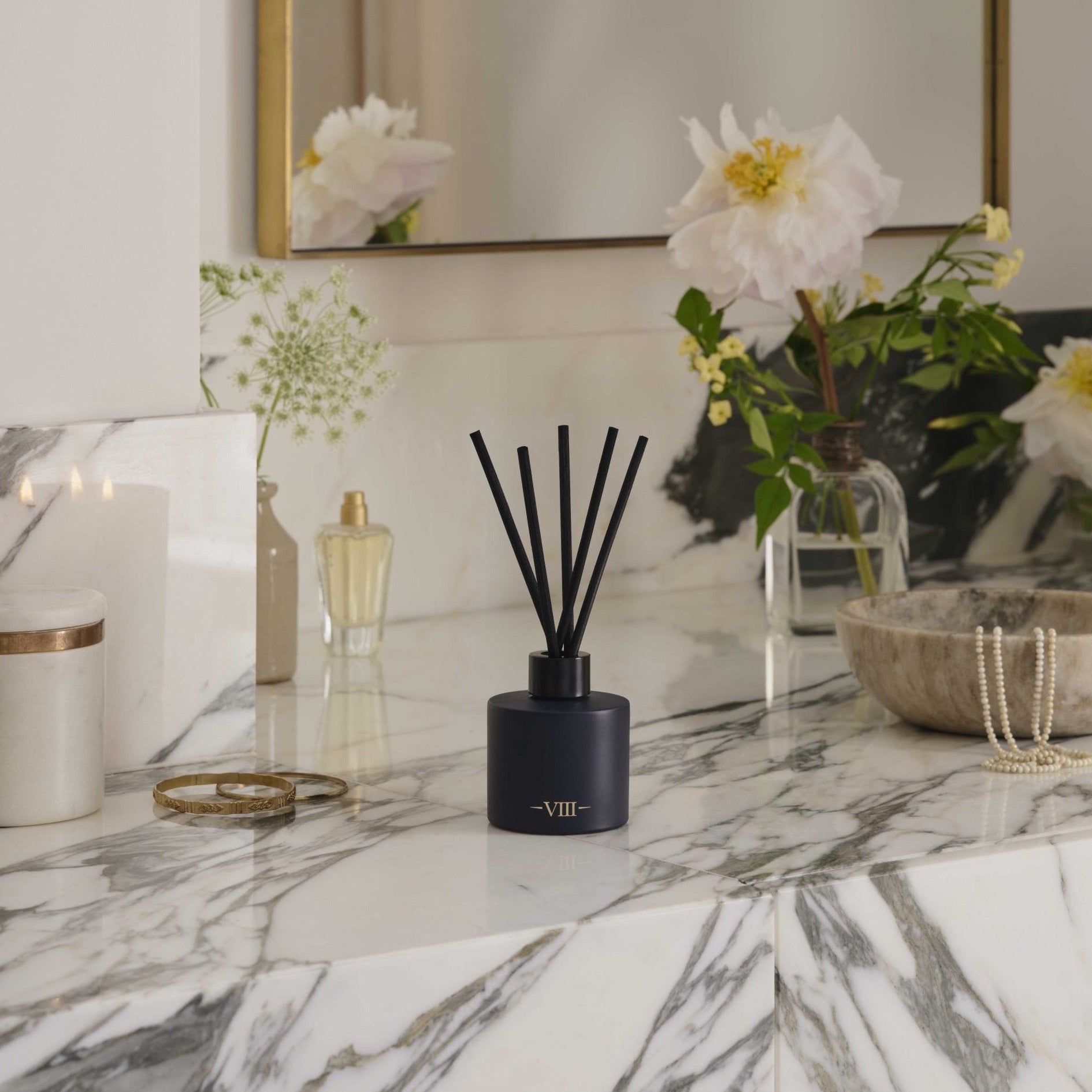 Black diffuser on a marble surface with decorative items in the background