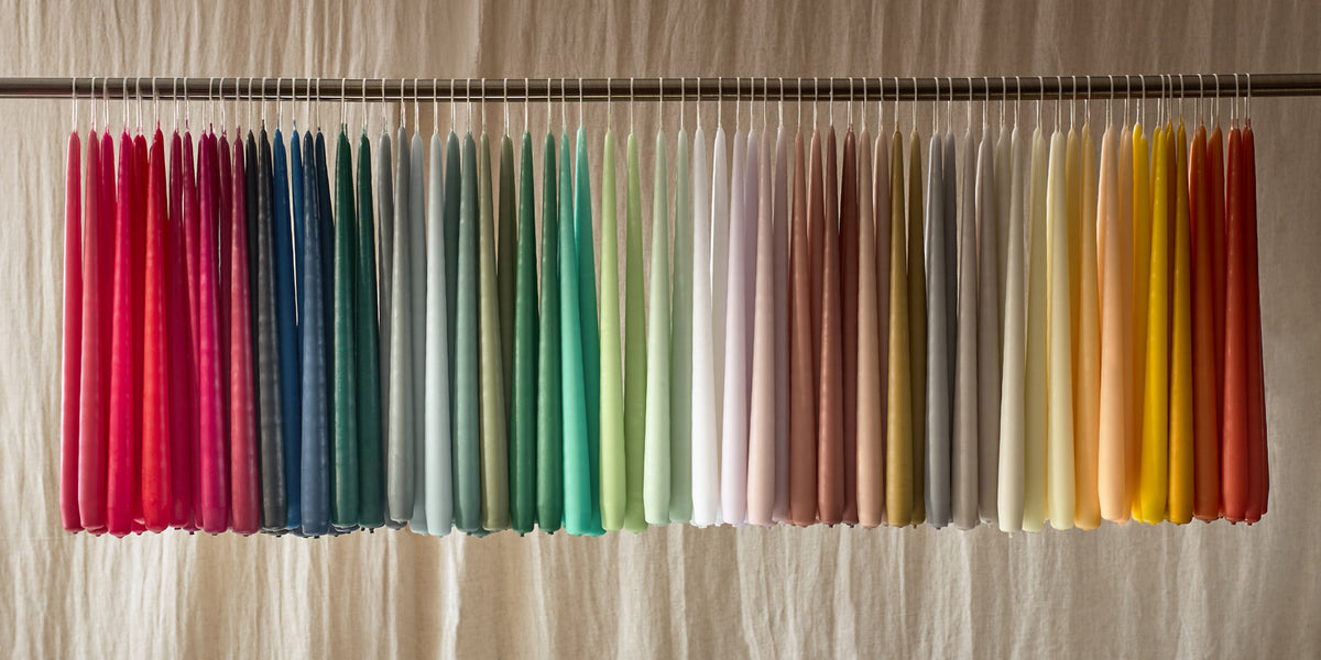 Charles Farris hand-dipped hanging pair dinner candles in a rainbow of colours, hung on a rail in our Wiltshire factory