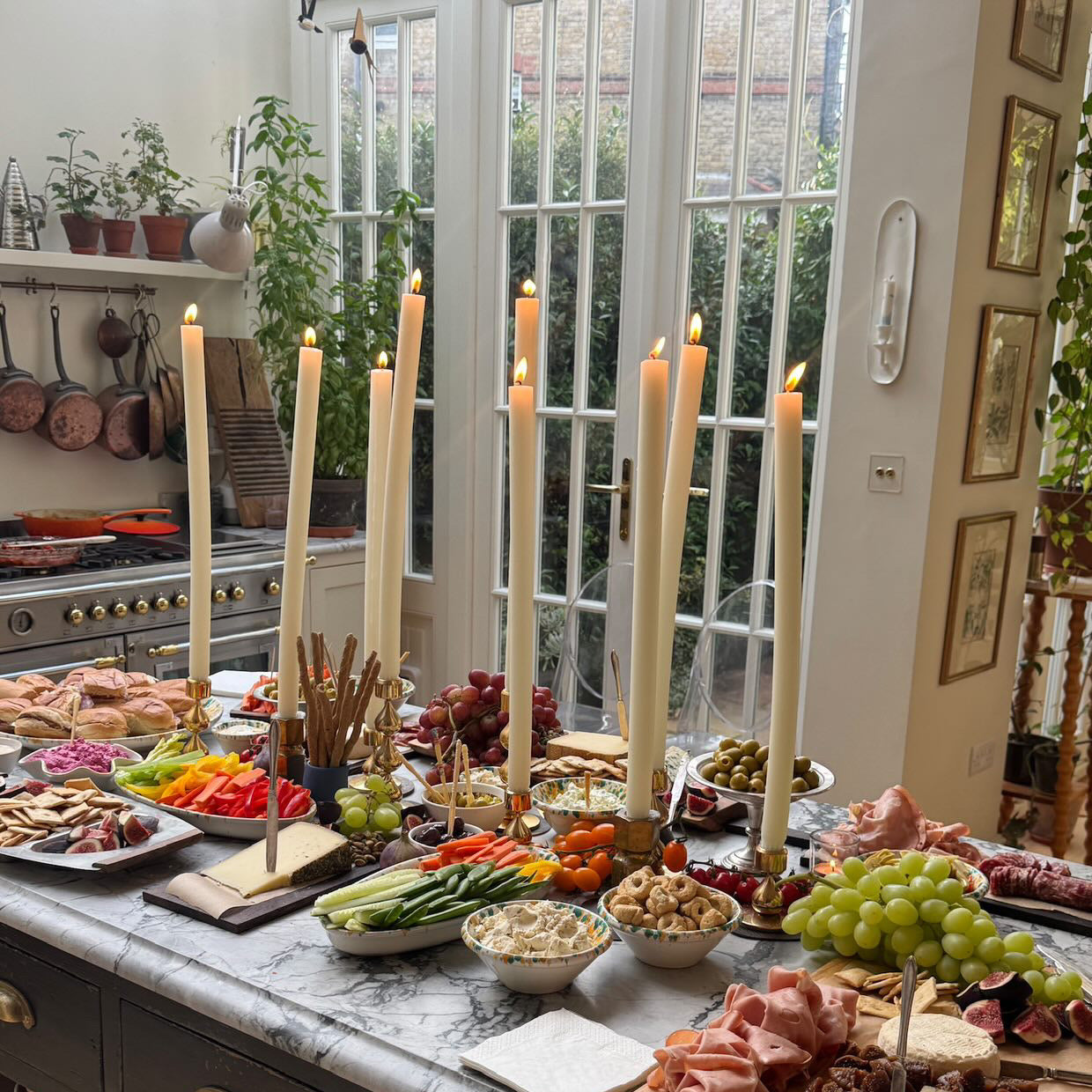 Dining room with a table set for a meal featuring dining candles, fruits, vegetables, and bread.