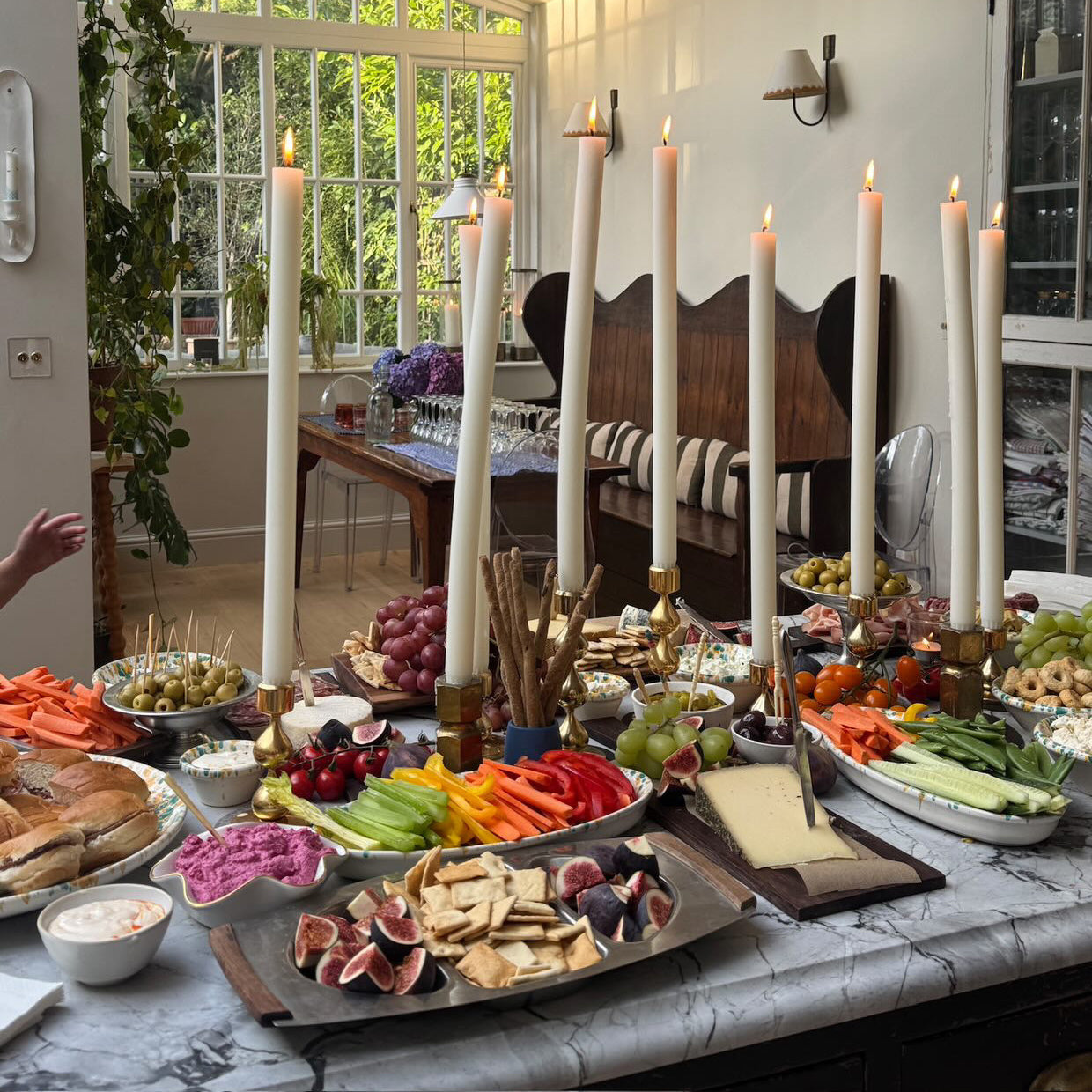 Dining room with a table set for a meal featuring dining candles, fruits, vegetables, and bread.