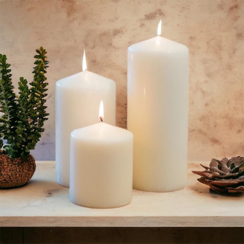 Three white candles on a wooden surface with a textured wall background
