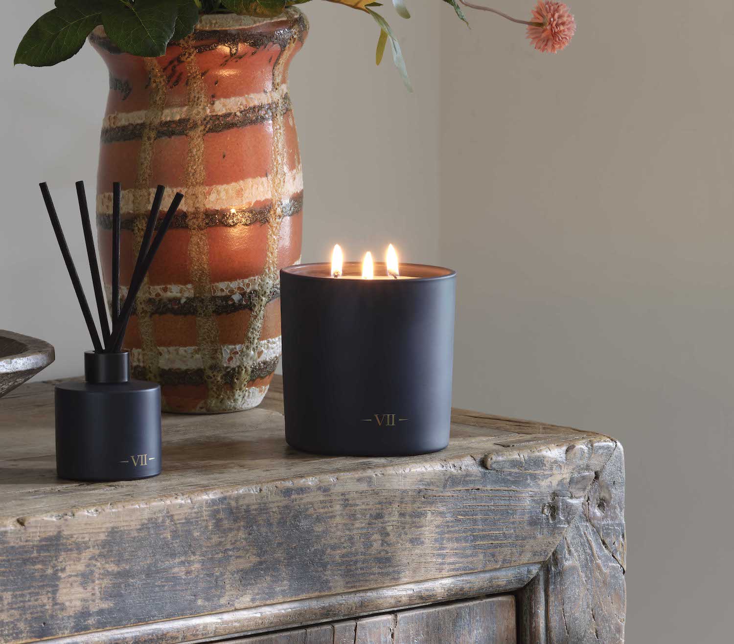 Candle with reed diffuser on a wooden surface with a neutral background