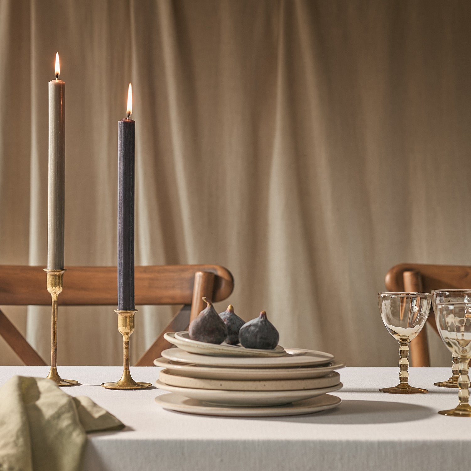 Two lit dinner candles on a table with plates