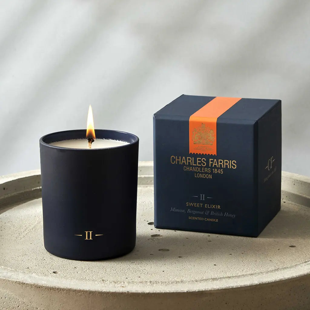 Candle and its packaging on a textured surface with a neutral background