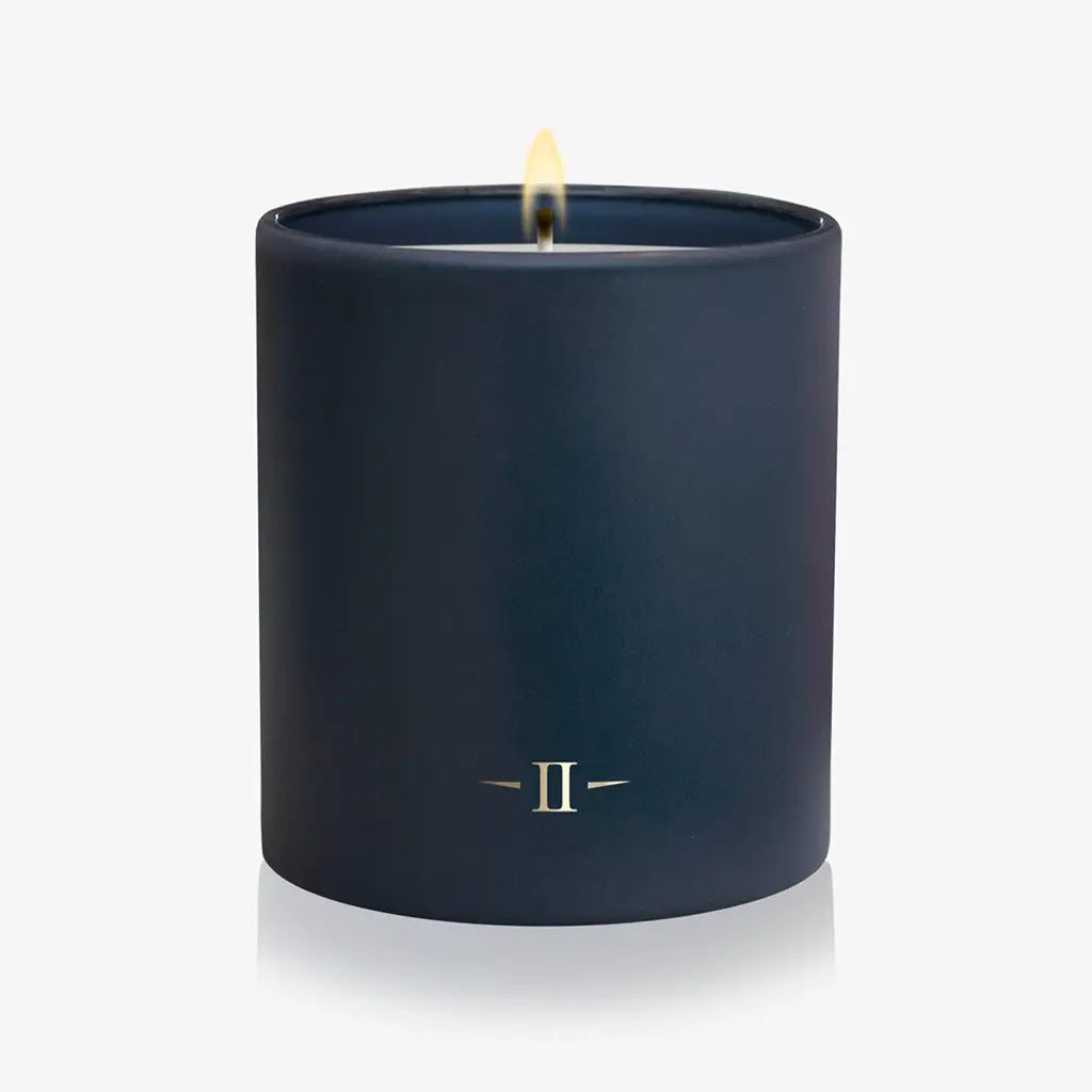 Navy blue candle with a small flame on a white background