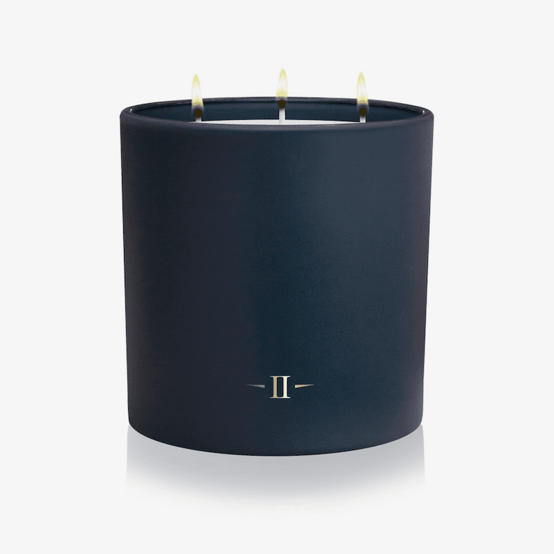 Navy blue candle with three wicks on a white background