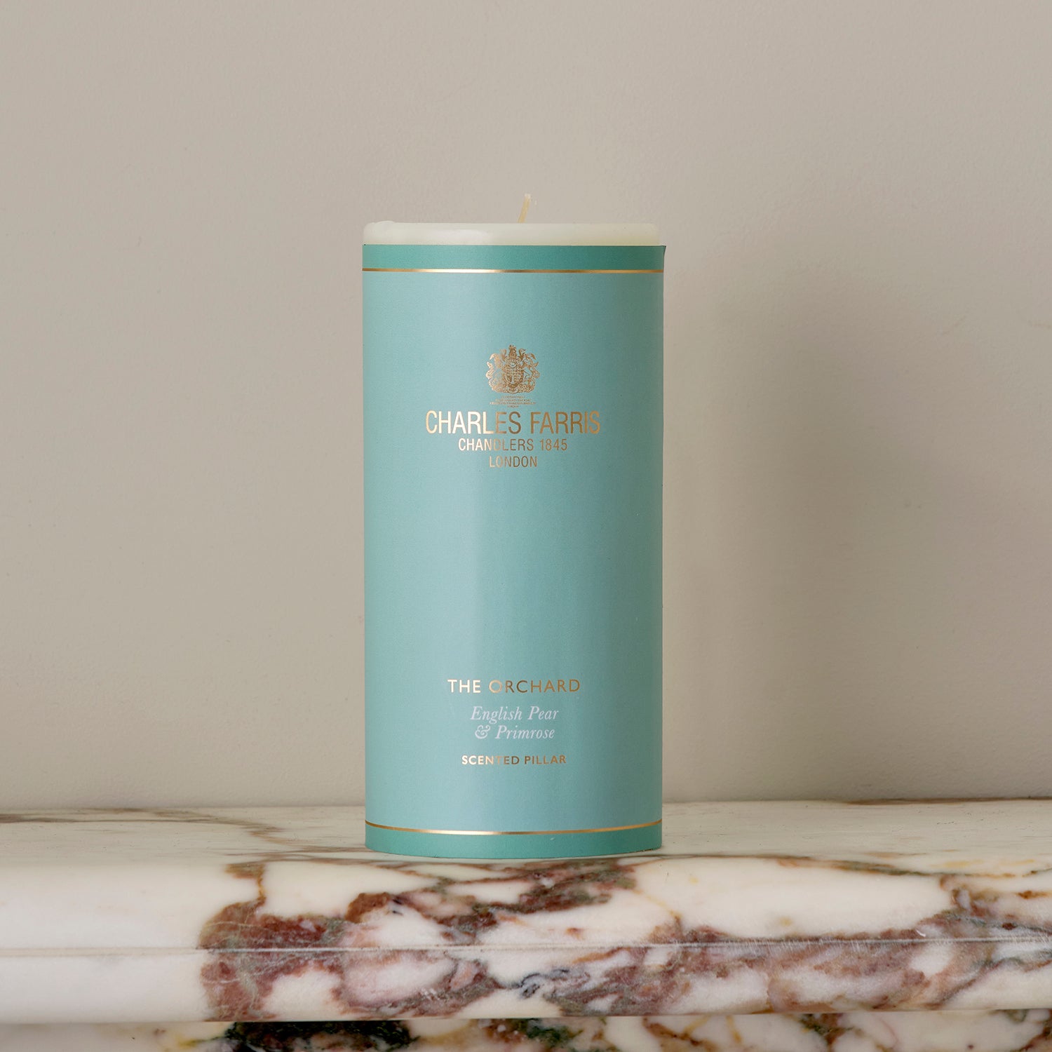 An Orchard Scented Pillar Candle on a marble surface.