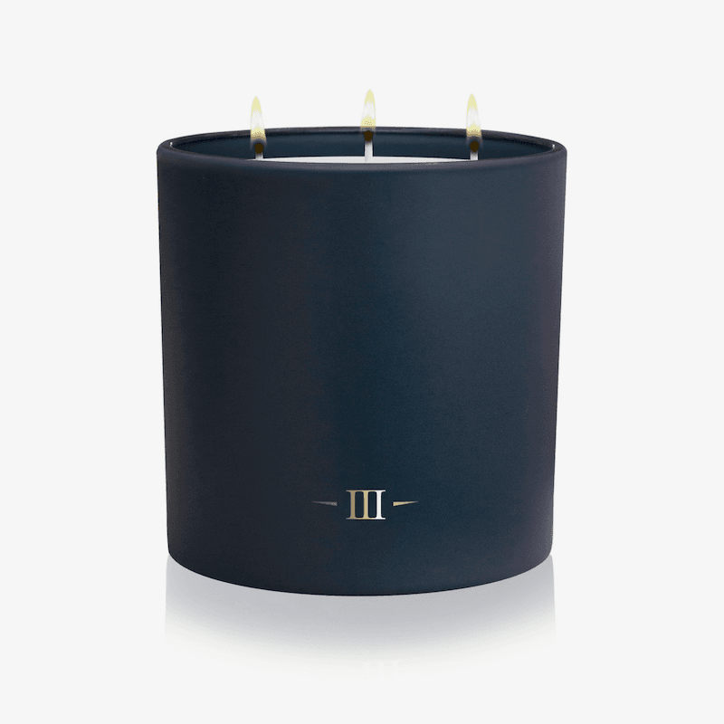 Navy blue candle with three wicks on a white background