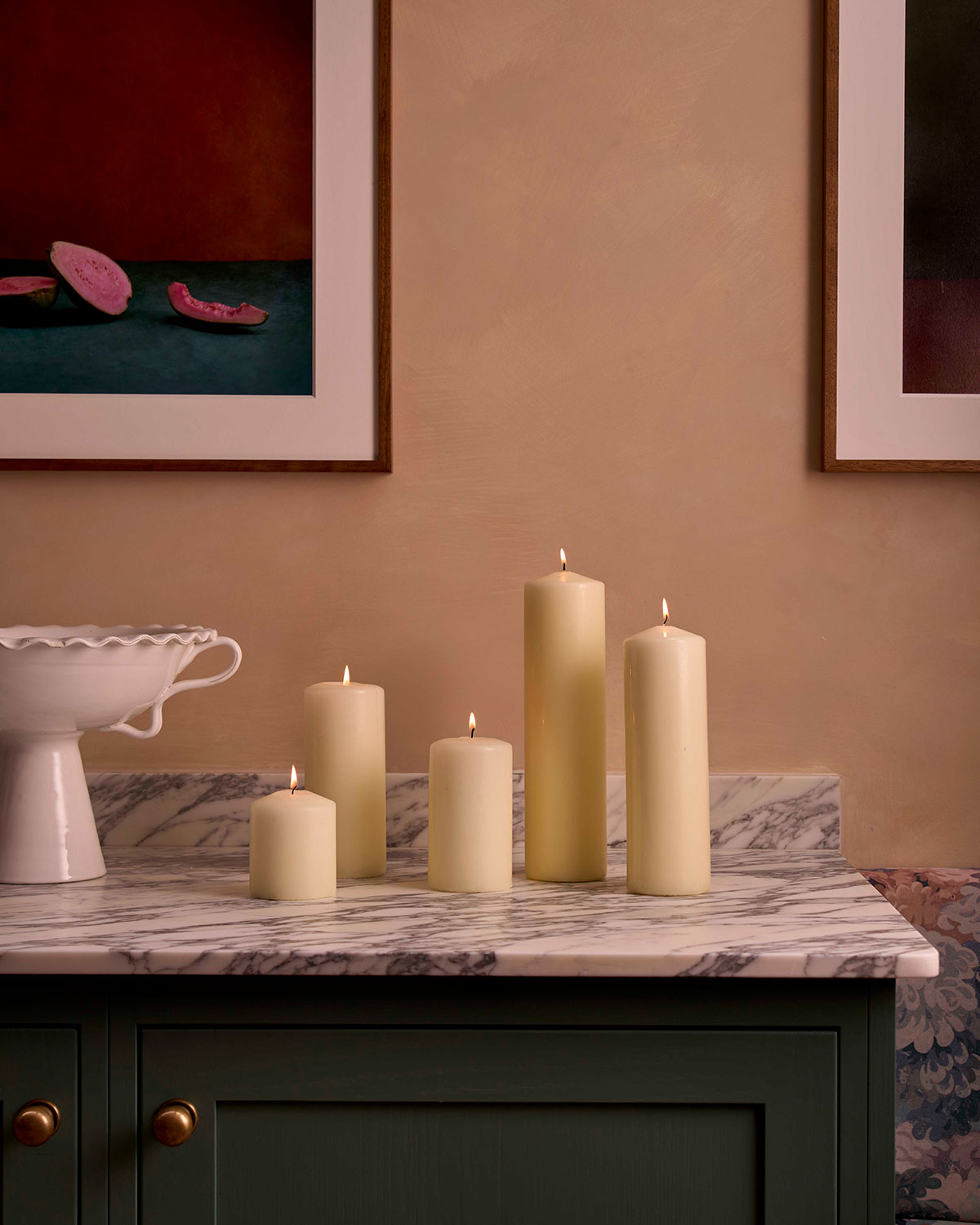 Charles Farris ivory pillar candles in graduated heights on a marble-topped sideboard