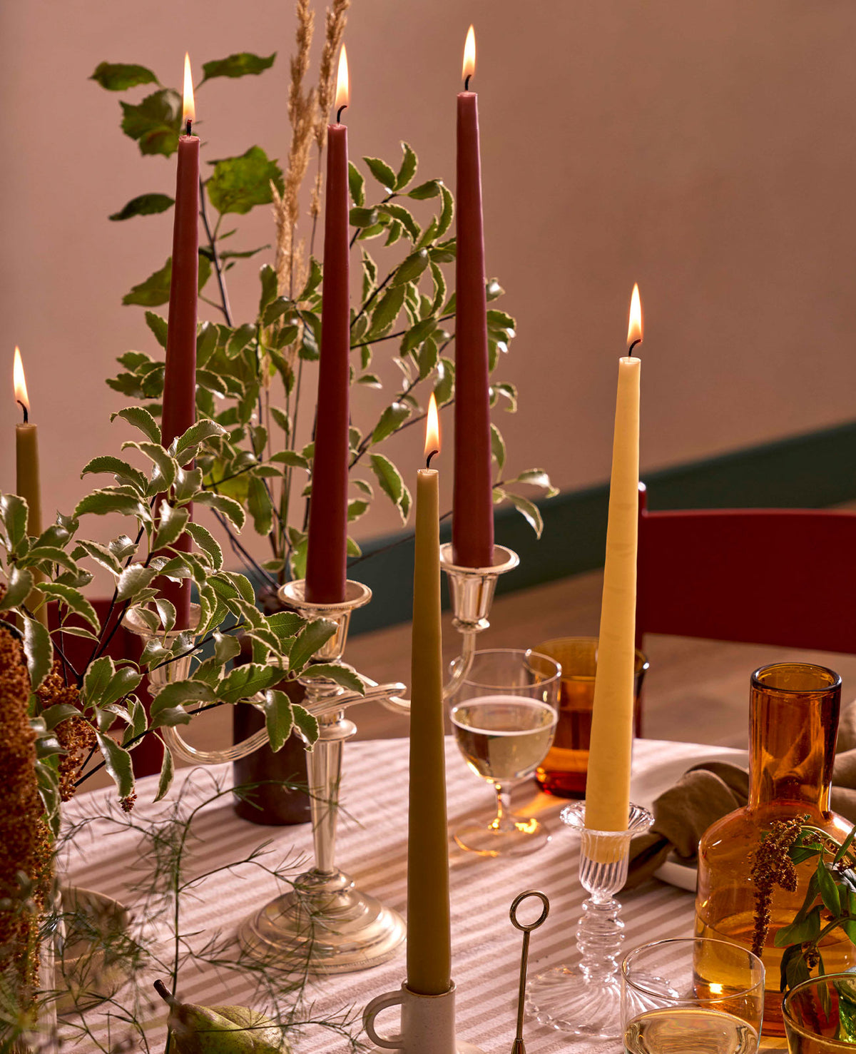 Charles Farris burgundy, olive and mustard tapered dinner candles lit in silver candlesticks among autumn foliage