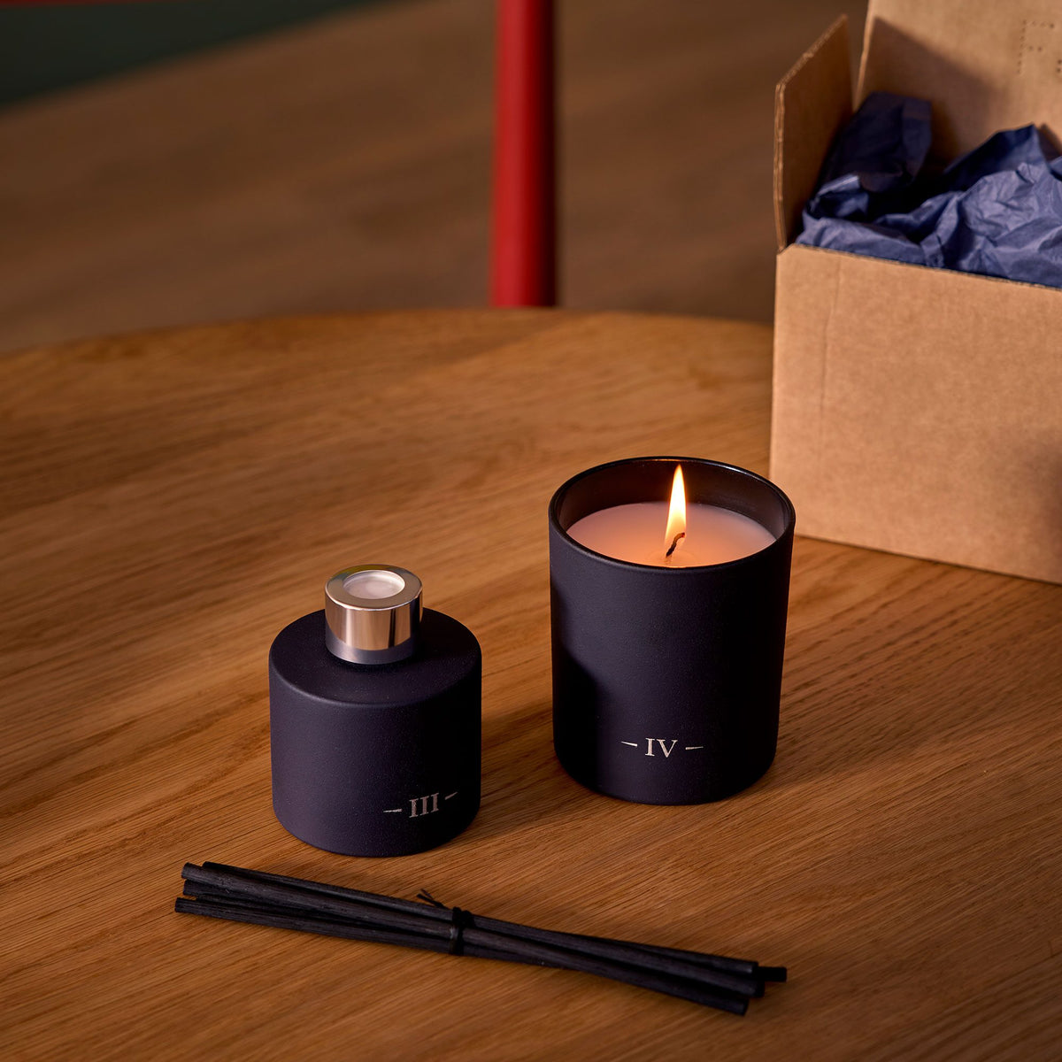 Charles Farris redolent Fig scented candle burning beside the Rubus reed diffuser and its reeds on an oak table