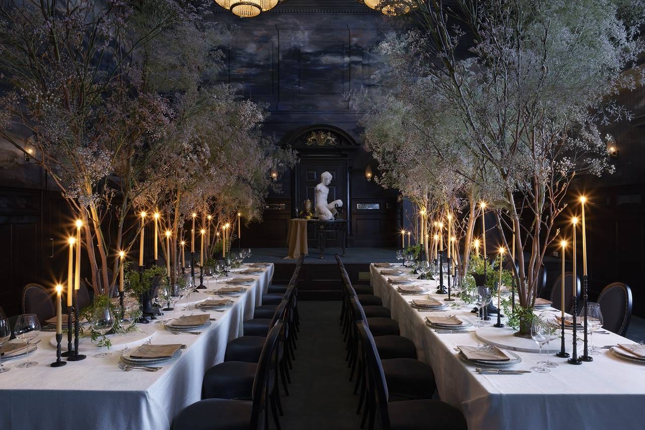 Candlelit private dining room set with tall Charles Farris dinner candles and trees for a corporate event