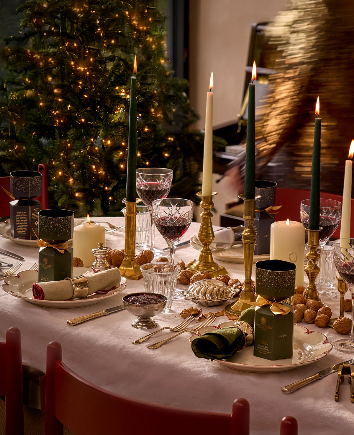 Charles Farris dinner candles lit on a Christmas table beside a decorated tree