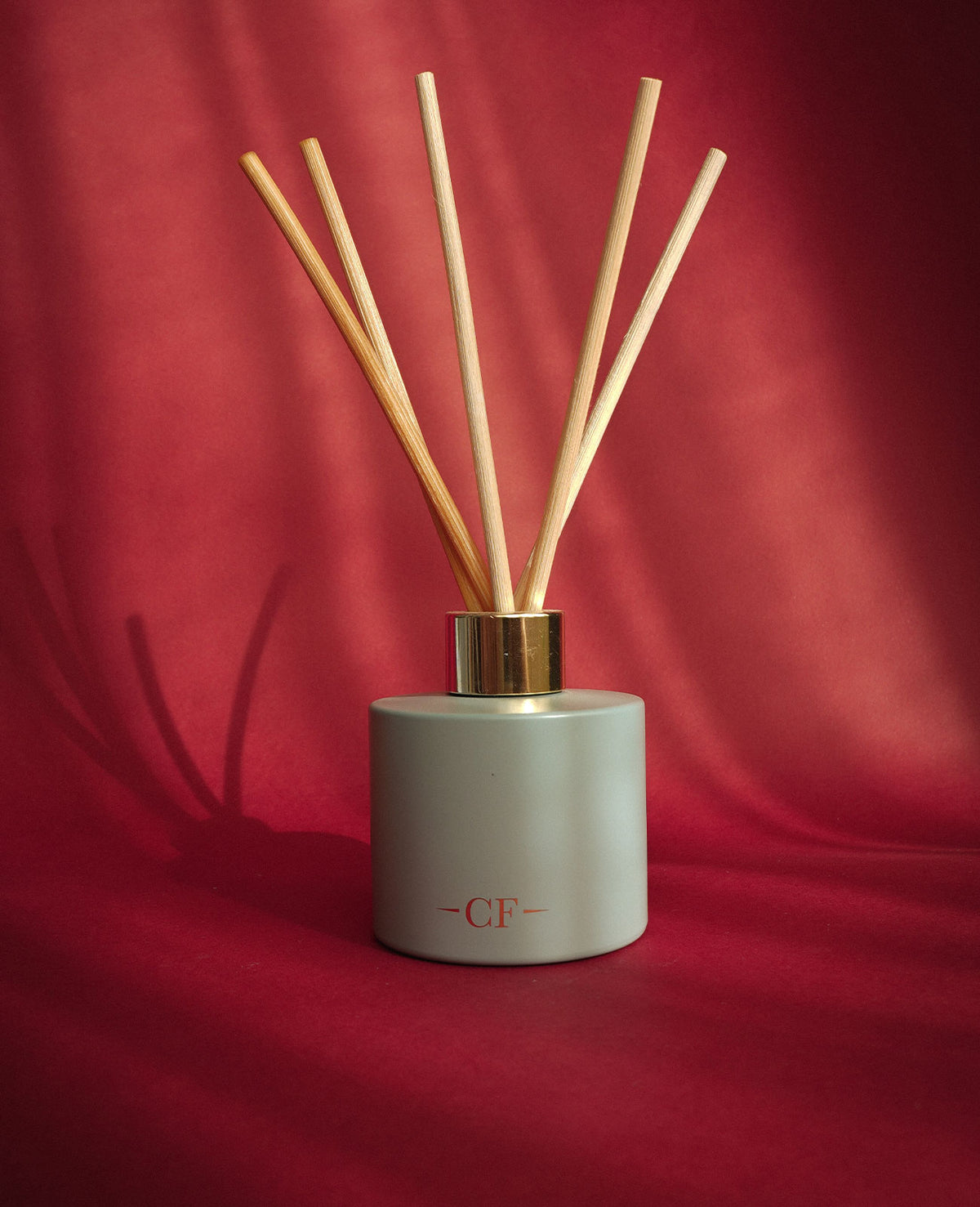 Charles Farris reed diffuser with natural reeds on red velvet
