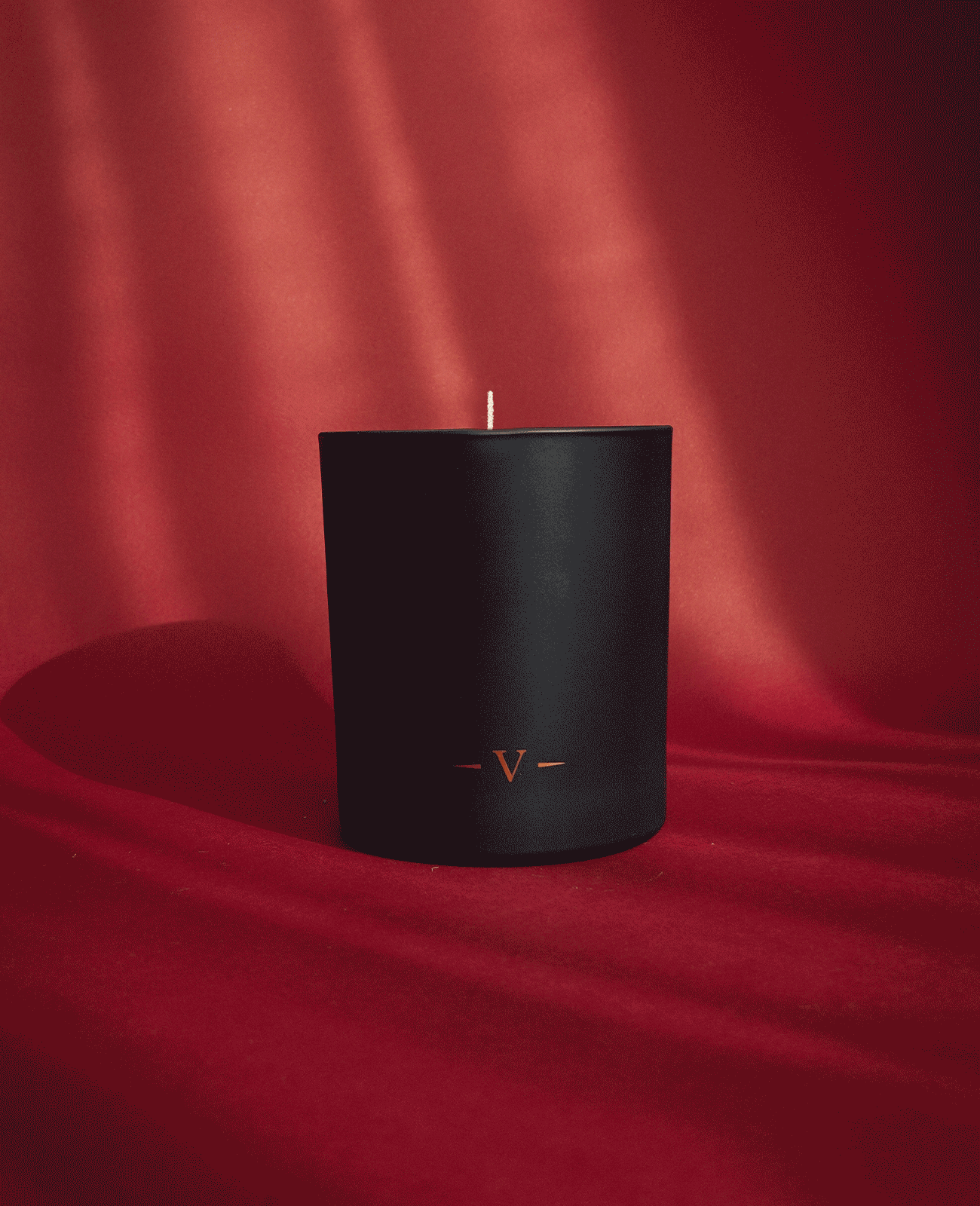 Charles Farris lit signature scented candle in a black glass on red velvet