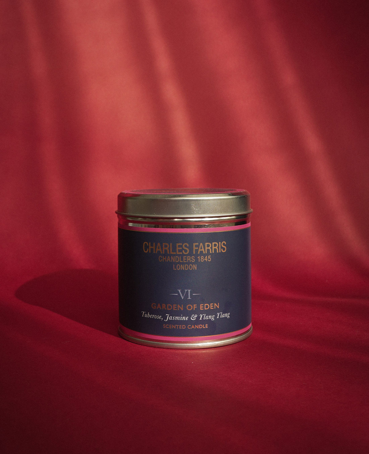 Charles Farris Garden of Eden signature tin candle on red velvet