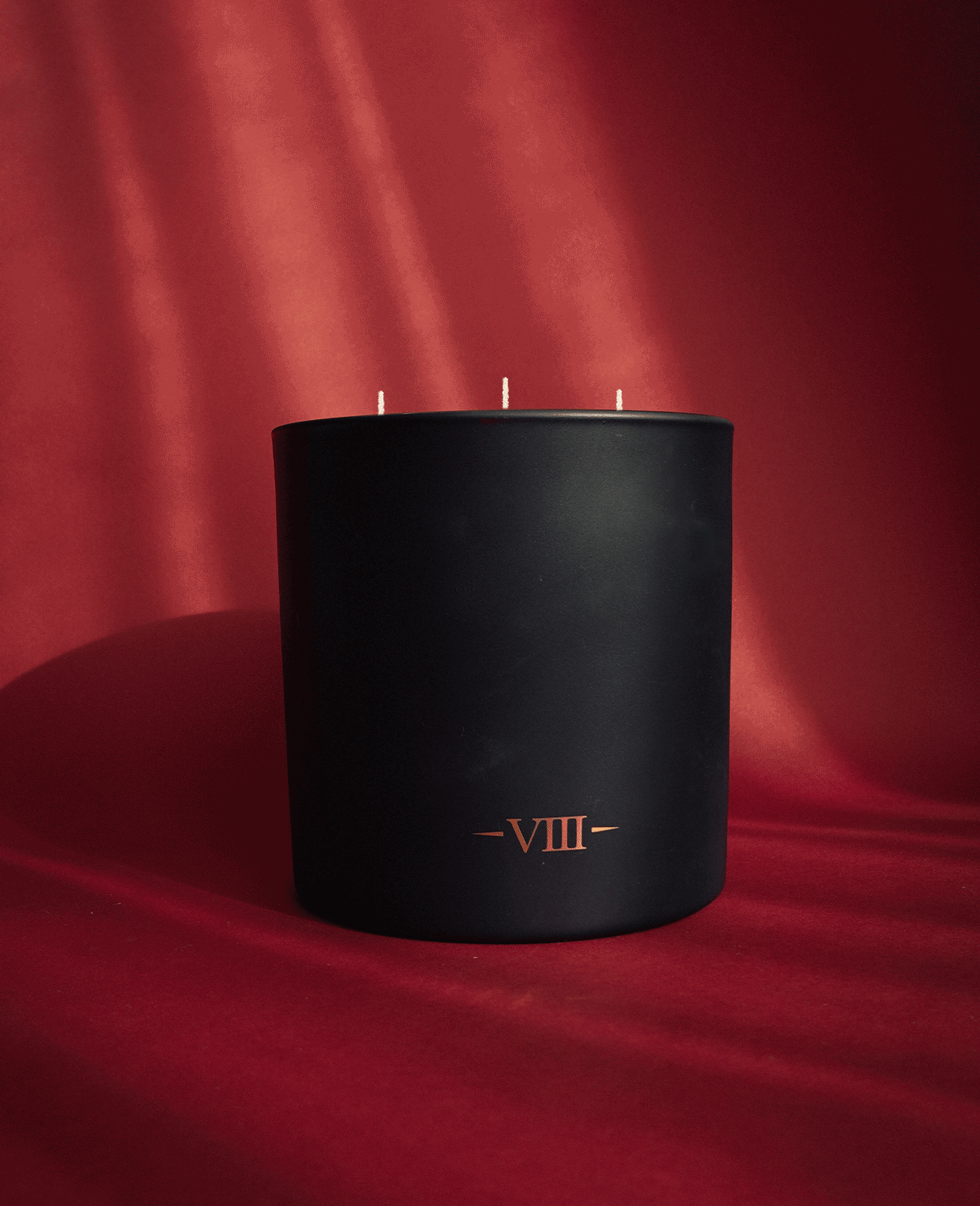 Charles Farris lit three-wick scented candle on red velvet