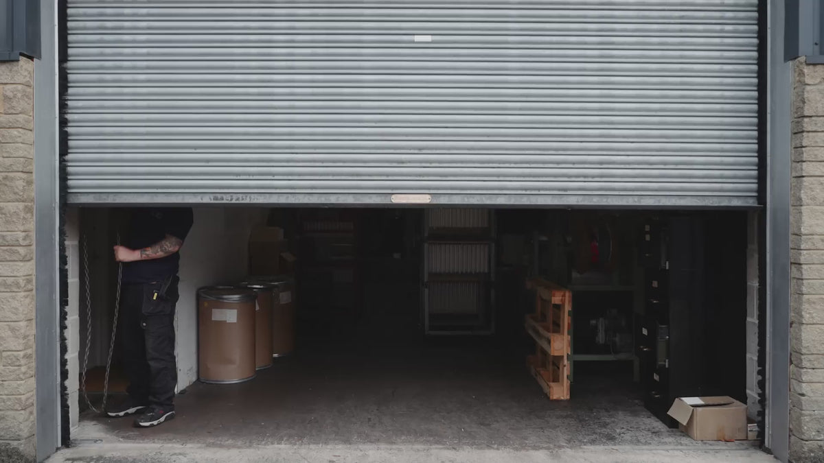 Inside the Charles Farris candle factory in Wiltshire: hanging pairs of tapered dinner candles are hand-dipped, trimmed and dried on racks, with colour swatches for Burnt Sun, Deep Ocean and Terracotta