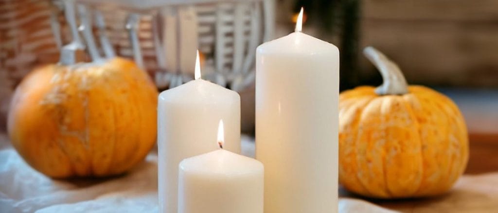 Three pillar candles by pumpkins