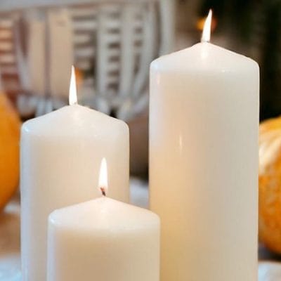 Three pillar candles by pumpkins